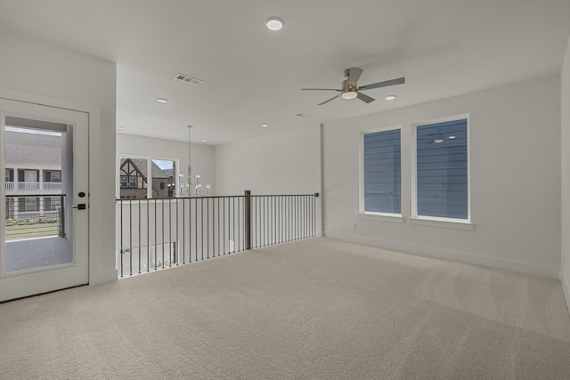 carpeted empty room featuring ceiling fan with notable chandelier