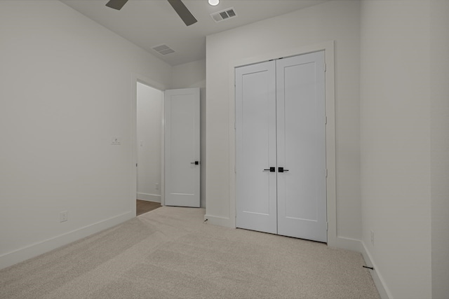 unfurnished bedroom with ceiling fan, light colored carpet, and a closet