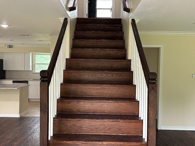 stairway featuring a textured ceiling, hardwood / wood-style floors, and crown molding