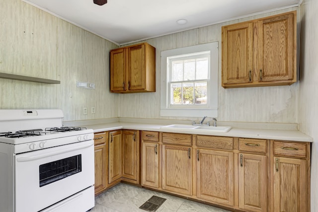 kitchen with sink, white gas range, and light tile floors