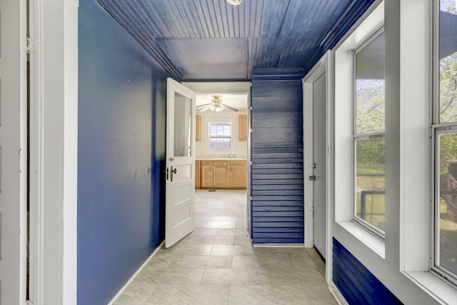 hall featuring wood ceiling, plenty of natural light, and light tile floors