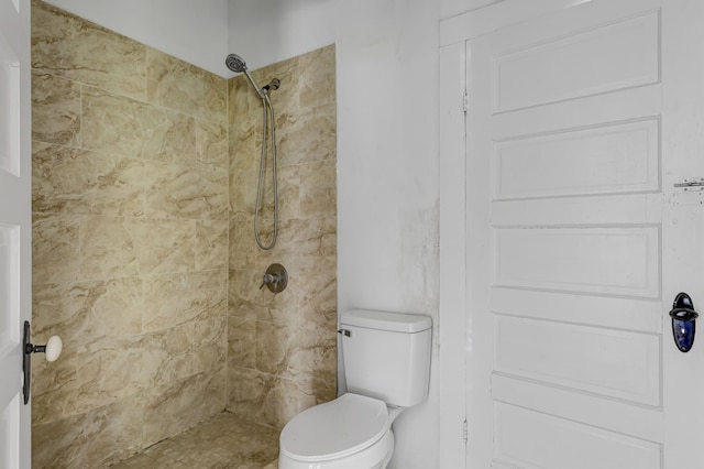 bathroom with a tile shower and toilet