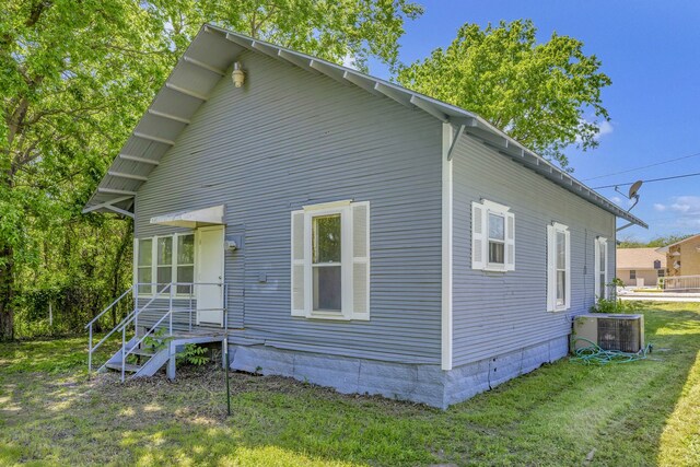 view of property exterior with a lawn and central AC