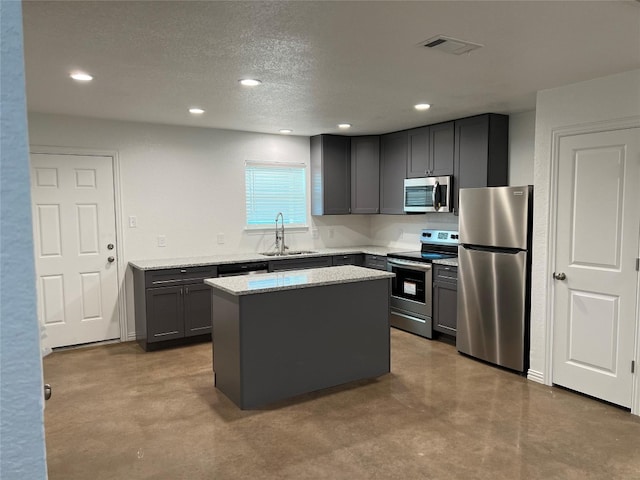 kitchen featuring light stone counters, stainless steel appliances, sink, gray cabinets, and a kitchen island