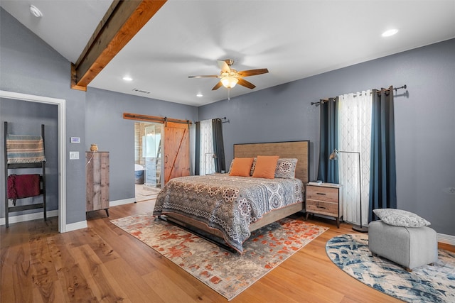 bedroom featuring a barn door, hardwood / wood-style floors, ceiling fan, and vaulted ceiling with beams