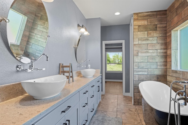 bathroom featuring double vanity, a soaking tub, a sink, and baseboards