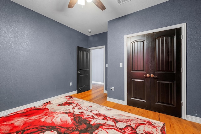 bedroom featuring baseboards, visible vents, a ceiling fan, wood finished floors, and a closet