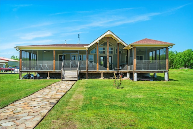 back of property with a sunroom and a lawn