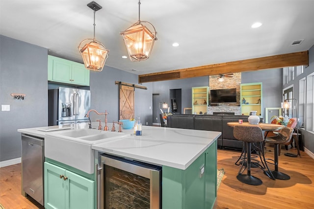 kitchen with stainless steel appliances, beverage cooler, green cabinets, and a barn door