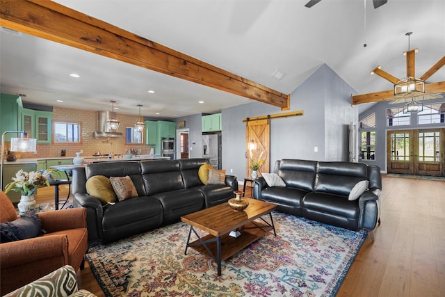 living room with plenty of natural light, a barn door, beamed ceiling, and french doors