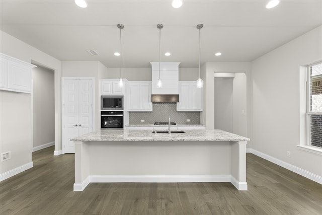 kitchen with light stone counters, pendant lighting, a kitchen island with sink, white cabinetry, and black oven