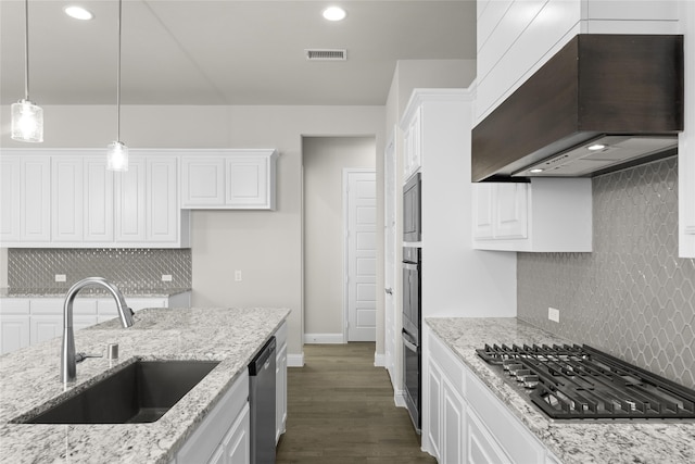 kitchen with white cabinets, sink, wall chimney range hood, appliances with stainless steel finishes, and light stone countertops