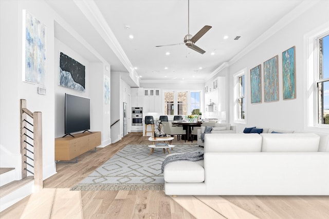 living room featuring light hardwood / wood-style flooring, ornamental molding, ceiling fan, and a wealth of natural light