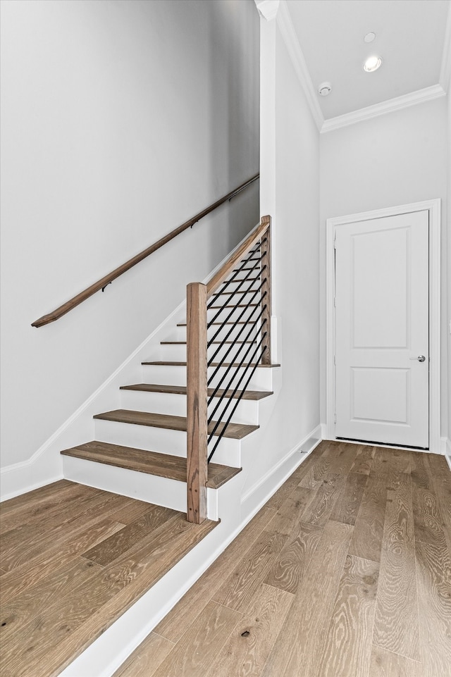 stairs with ornamental molding and hardwood / wood-style floors