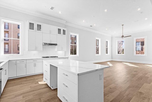 kitchen featuring ornamental molding, a center island, light wood-type flooring, and white cabinets