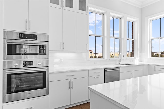 kitchen featuring a healthy amount of sunlight, sink, stainless steel appliances, white cabinets, and light stone counters