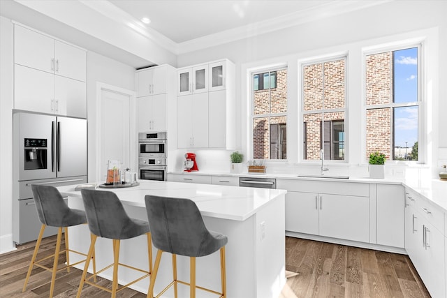 kitchen featuring appliances with stainless steel finishes, sink, a kitchen island, white cabinetry, and dark hardwood / wood-style floors