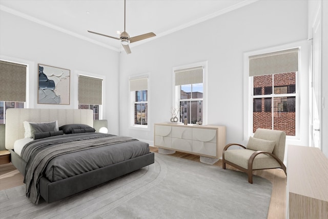 bedroom with crown molding, light wood-type flooring, and ceiling fan