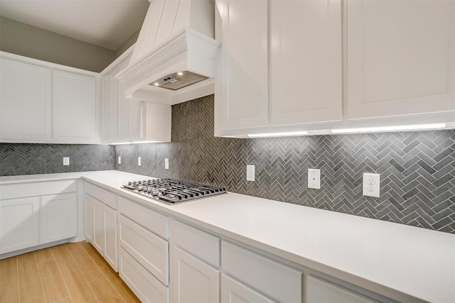 kitchen featuring custom range hood, light wood-type flooring, stainless steel gas cooktop, and white cabinets