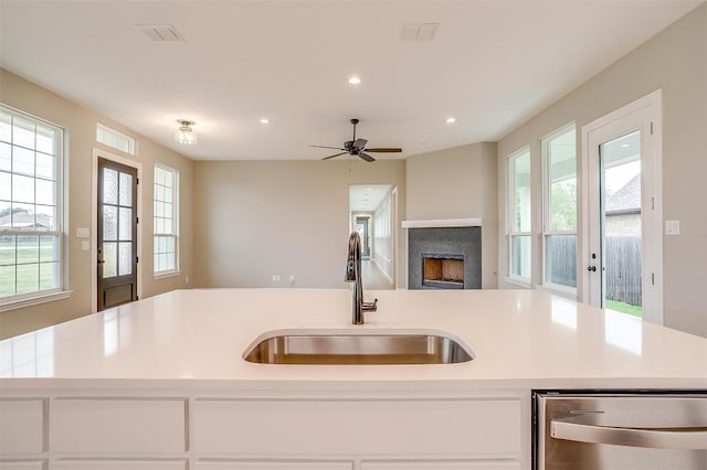 kitchen featuring ceiling fan, a kitchen island with sink, dishwasher, and sink