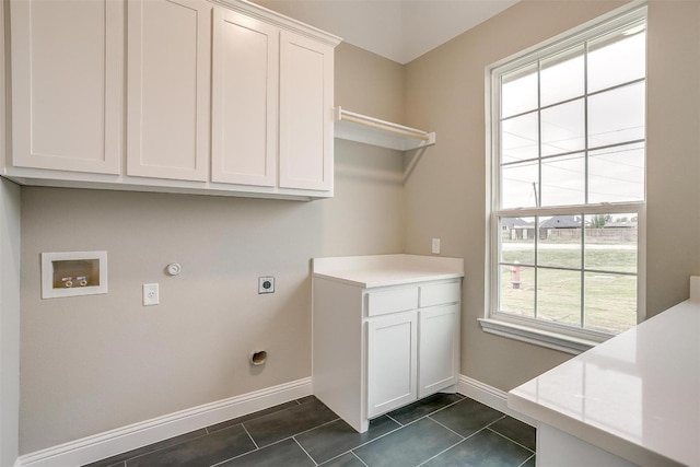 washroom with hookup for an electric dryer, hookup for a washing machine, hookup for a gas dryer, dark tile flooring, and cabinets