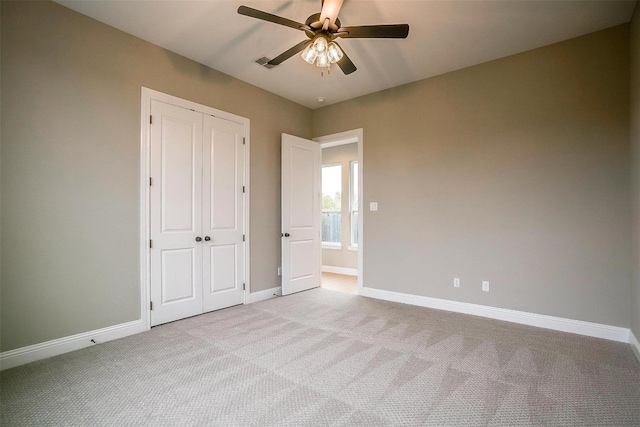 unfurnished bedroom with light colored carpet, a closet, and ceiling fan