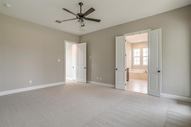 unfurnished bedroom with light colored carpet, ceiling fan, and ensuite bathroom