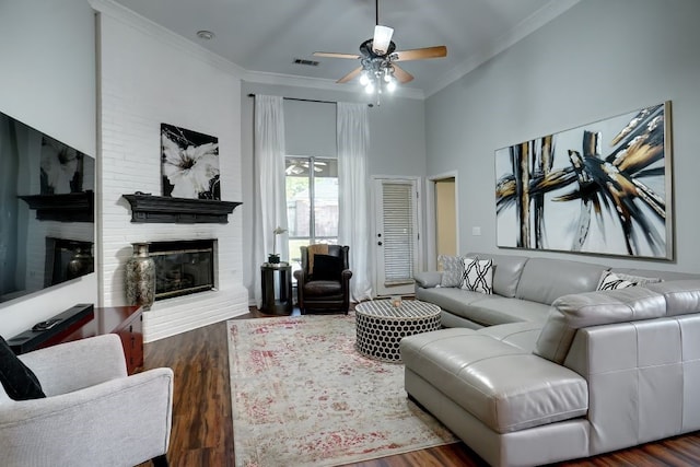 living room featuring ornamental molding, dark hardwood / wood-style flooring, ceiling fan, and a brick fireplace