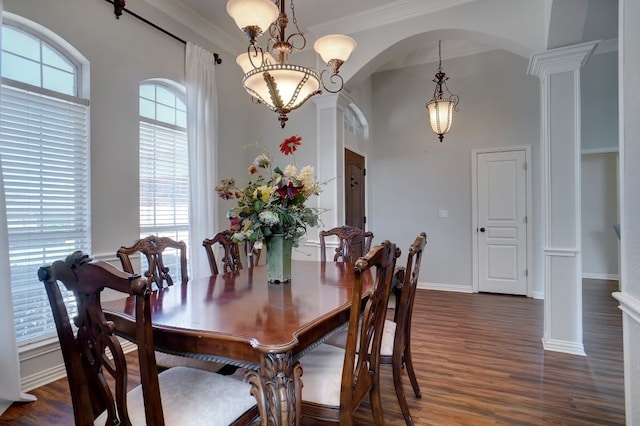 dining area featuring ornamental molding, dark wood-type flooring, ornate columns, and a notable chandelier