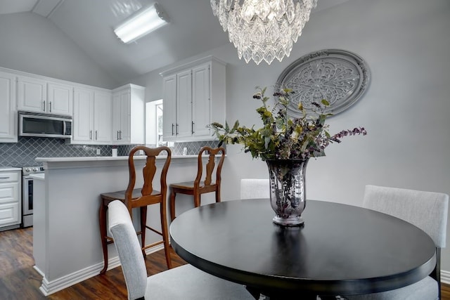 dining room with a chandelier, dark wood-type flooring, and lofted ceiling