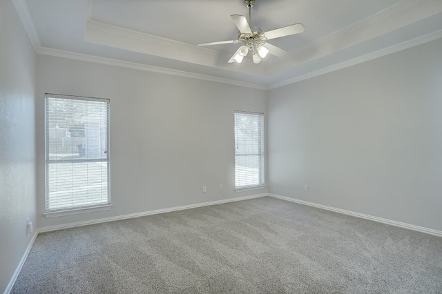 spare room featuring light colored carpet, ceiling fan, a tray ceiling, and crown molding