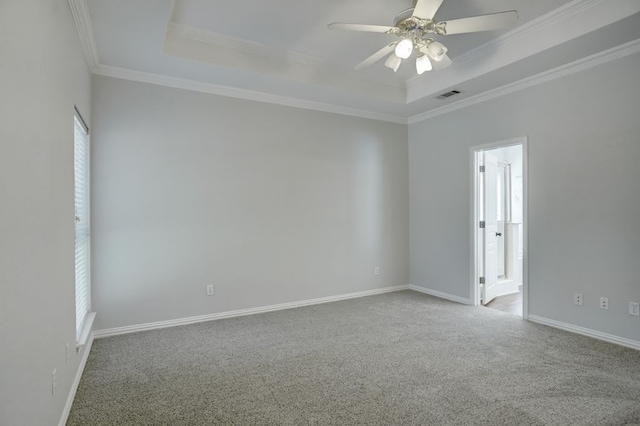 carpeted empty room with ceiling fan, crown molding, and a raised ceiling