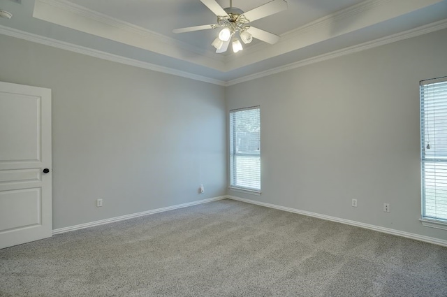 carpeted empty room featuring plenty of natural light, a raised ceiling, ceiling fan, and ornamental molding