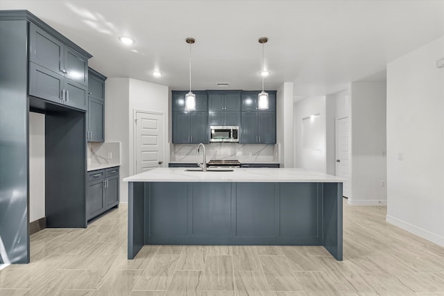 kitchen with an island with sink, light stone countertops, decorative light fixtures, and sink