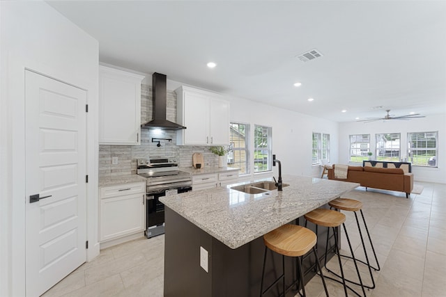 kitchen with white cabinets, sink, a kitchen bar, wall chimney range hood, and range with electric stovetop