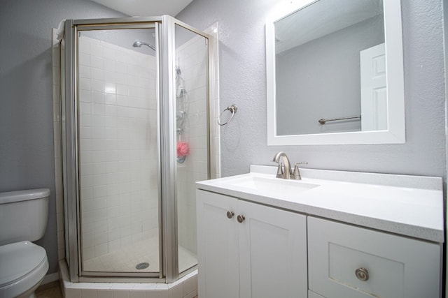 bathroom featuring a shower with shower door, toilet, and vanity