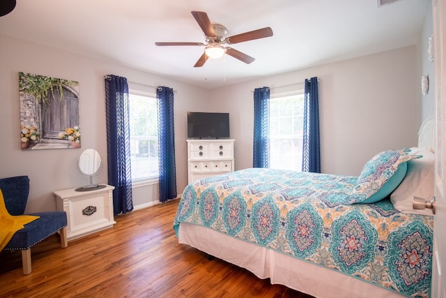 bedroom with ceiling fan, light hardwood / wood-style floors, and multiple windows