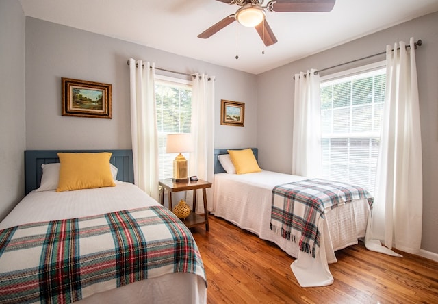 bedroom featuring light hardwood / wood-style floors, ceiling fan, and multiple windows