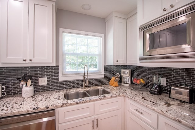 kitchen with sink, appliances with stainless steel finishes, tasteful backsplash, and white cabinetry