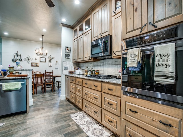 kitchen with appliances with stainless steel finishes, backsplash, dark wood-type flooring, pendant lighting, and an inviting chandelier