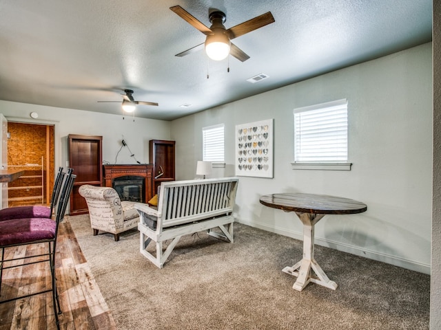 living room with ceiling fan, hardwood / wood-style flooring, and a textured ceiling