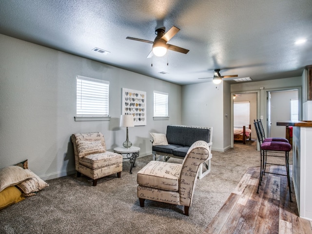 carpeted living room featuring ceiling fan and a textured ceiling