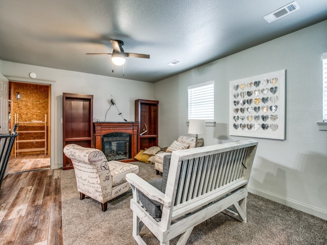 living room featuring wood-type flooring, ceiling fan, and a textured ceiling