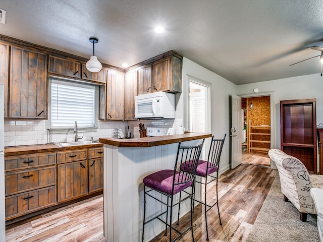 kitchen featuring wood-type flooring, sink, a healthy amount of sunlight, and hanging light fixtures