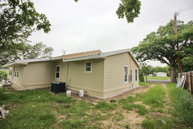 view of side of property with a lawn and central AC