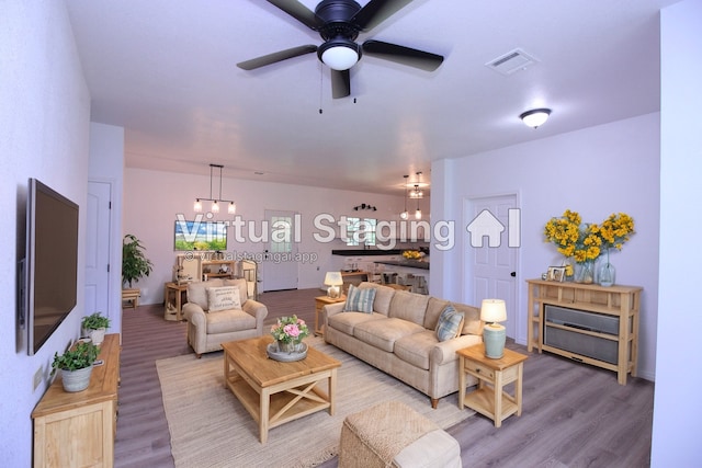 living room with ceiling fan with notable chandelier and hardwood / wood-style floors