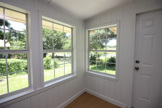 doorway to outside with wooden walls, plenty of natural light, and hardwood / wood-style floors