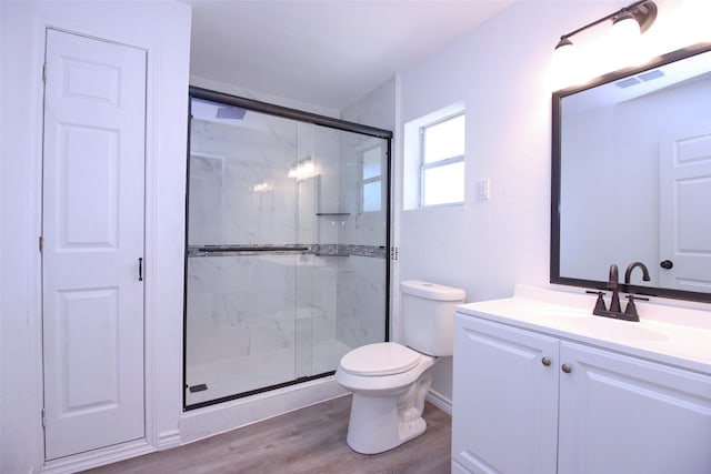 bathroom featuring hardwood / wood-style flooring, a shower with door, vanity, and toilet