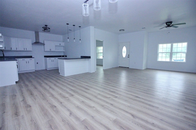 kitchen with light hardwood / wood-style floors, wall chimney exhaust hood, ceiling fan, and white cabinets