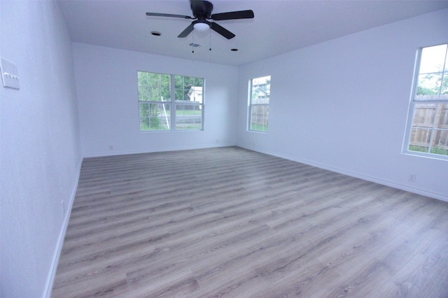 spare room with ceiling fan, light wood-type flooring, and a wealth of natural light